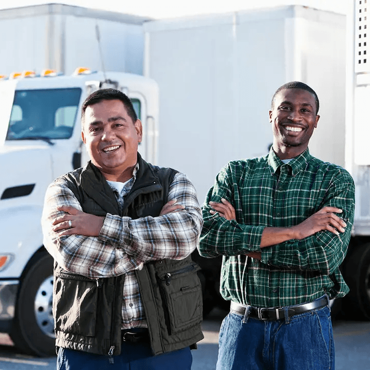 Two commercial truck drivers standing in front of their trucks